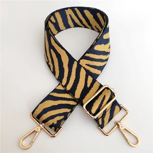 Close-up of zebra pattern wide bag strap with golden metal lobster clasps and buckle