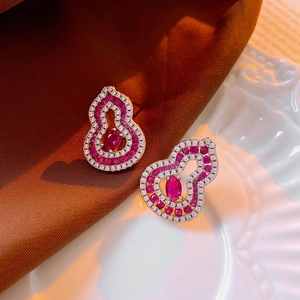 Détail macro de boucles d'oreilles gourde en argent avec pierres rouges et cristaux