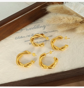 Close-up of golden twisted rope hoop earrings with silicone backs on elegant background