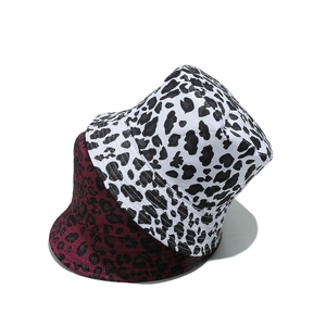 Detail of leopard and cow print bucket hats in white and dark red cotton twill fabric