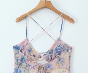 Detail of floral backless dress with cross straps and lace-up design on wood hanger