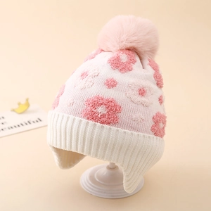 Detail of winter knit hat featuring pink floral pattern and large faux fur pom-pom