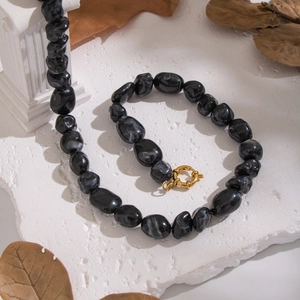 Detail of irregular black resin beads with golden clasp and starfish necklace elements
