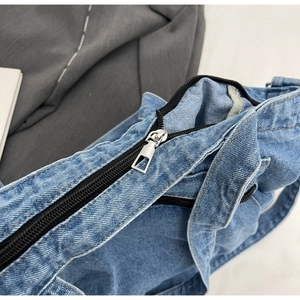 Detailed close-up of blue denim tote bag showing fabric texture and silver metal zipper