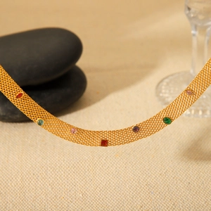 Macro shot of colorful round and square gemstones on a gold mesh chain necklace