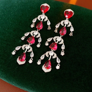 Macro detail of luxury silver earrings featuring red heart and water drop zircons