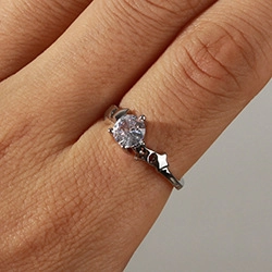 Close-up of a silver-colored ring with a sparkling round diamond-cut zircon stone