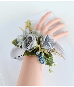 Detail of elegant dusty blue faux rose wrist corsage with berries and white ribbon