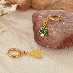 Detailed macro view of colorful enamel Christmas tree earrings on natural stone background
