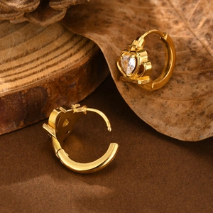 Detail of gold crown hoop earrings with heart shaped crystal on vintage wood background
