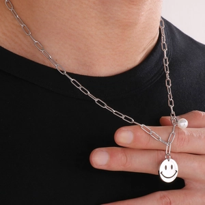 Detail of silver paperclip chain necklace with hollow smiley face pendant and white pearl