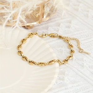 18K gold plated stainless steel coffee bean link bracelet on white shell tray