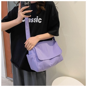 Detail of purple oxford cloth crossbody bag with flap closure and side pocket on model