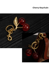 Detailed close-up of a double cherry charm featuring gold leaves and a lobster clasp