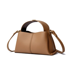 Detailed view of the brown pebble leather texture and sturdy handle on this square handbag