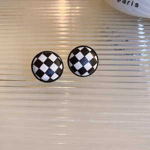 Close-up of vintage round black and white checkered earrings with silver needle posts