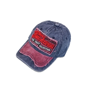 Detailed view of heavy washed denim baseball cap with distressed embroidery and red brim