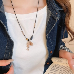 Close-up of a handmade wooden fish pendant with tassel on a beaded necklace cord