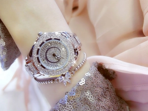 Macro shot of a luxury silver watch with full rhinestone inlay and flower charm bracelet