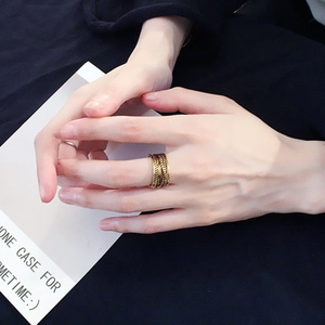 Close-up of a wide golden textured ring on a hand with minimalist aesthetic background