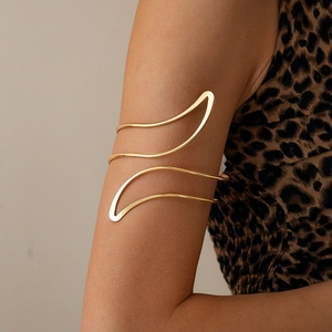 Detail of a wavy irregular gold arm cuff on a female model with a leopard print background