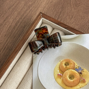 Detailed shot of dark tortoise shell acetate bow hair claw clip with gold lettering