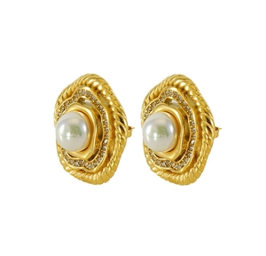 Dettaglio di orecchini vintage dorati con perla centrale, strass e trama a corda intrecciata