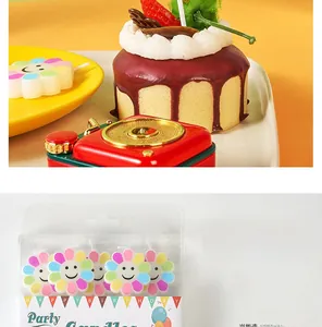 Macro detail of colorful smiling sunflower party candles in transparent hanging gift box