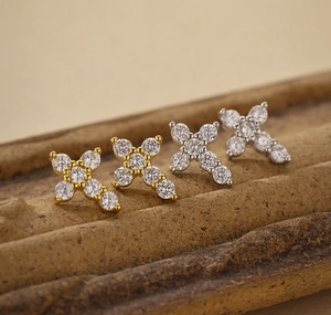 Macro shot of gold and silver S925 sterling silver cross stud earrings with sparkling zircons