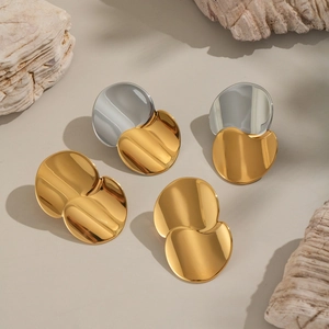 Minimalist two-tone and gold circular geometric mirror earrings on natural props