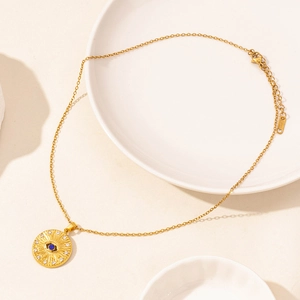Detailed close-up of golden evil eye pendant necklace on a white ceramic plate background
