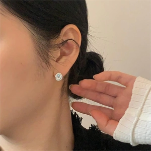 Close-up of minimalist silver earring with iridescent gemstone worn on an ear