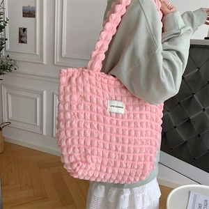 Close-up of pink cloud bubble flower tote bag with a woven brand tag on textured fabric