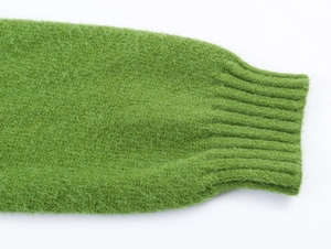 Vista macro dei polsini in maglia a coste verde erba e texture in morbido mohair