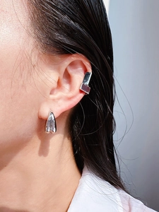 Detail shot of futuristic silver geometric cuff earring and drop set worn by model
