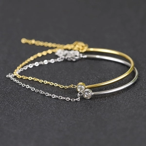 Close-up of 18K gold and silver stainless steel chain bracelets with zircon accents