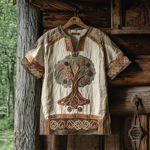 Detail of tree of life embroidery on beige linen short sleeve shirt hanging in forest
