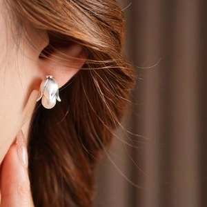 Close-up of vintage flower pearl stud earring on model's ear with silver texture