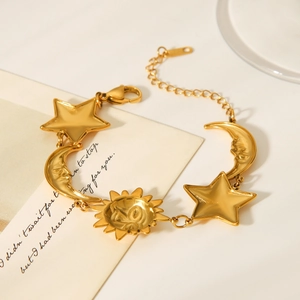 Macro detail of 18K gold star and moon charms with sun pendant on celestial bracelet