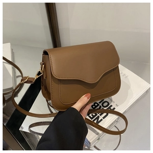 Detailed view of dark brown crossbody bag with refined stitching and gold hardware