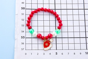 Close-up of kids Christmas pearl bracelet featuring festive red beads and Santa hat charm