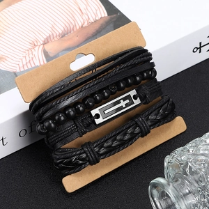 Détail de bracelets multicouches en cuir noir avec croix en métal et perles tressées