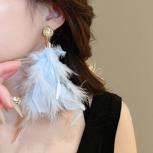 Macro shot of elegant light blue feather tassel earrings with pearl stud details