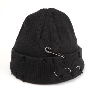 Detailed view of black distressed knit beanie with silver safety pin and metal rings