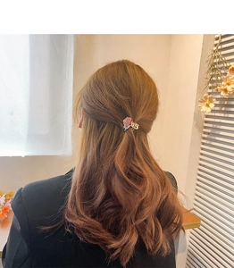 Detailed back view of a pink flower hair claw clip on brown wavy hair showing elegant styling