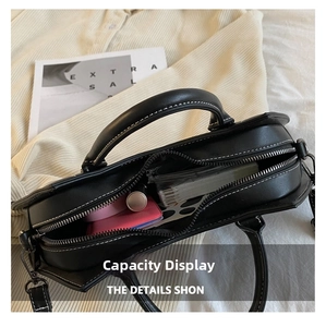 Interior view of black leather bat bag showing capacity for lipstick and notepad