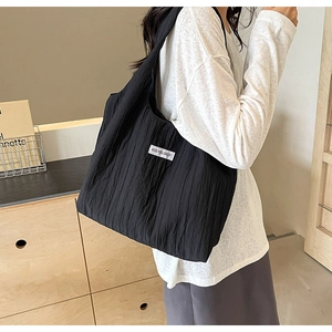 Detail der schwarzen Nylon-Tasche mit Faltenstruktur und weißem KISS YOURSELF-Label