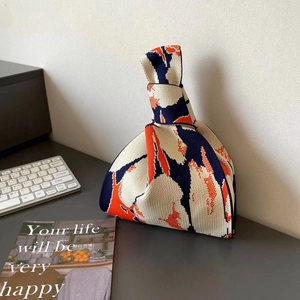 Detailed close-up of navy and orange floral knit bag on a modern desktop setting