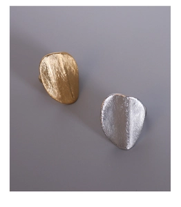 Detail of irregular matte gold and silver rings with brushed metal texture