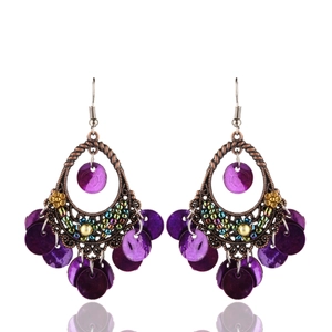 Dettaglio di orecchini boho con cornice in bronzo e nappe di conchiglie viola